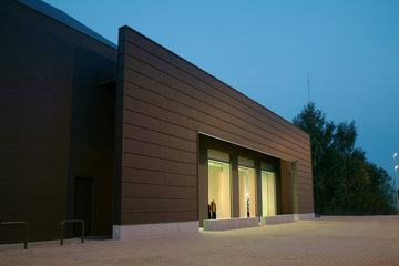 Buitenzijde van de Wellens kledingwinkel bij schemering, met een moderne gevel en grote verlichte etalageramen.